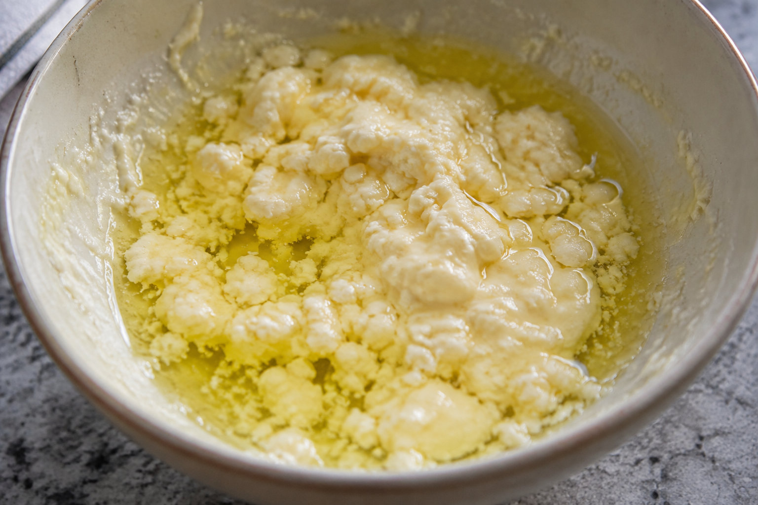 Une mayonnaise tranchée montrant une nappe d'huile séparée et une texture grumeleuse.